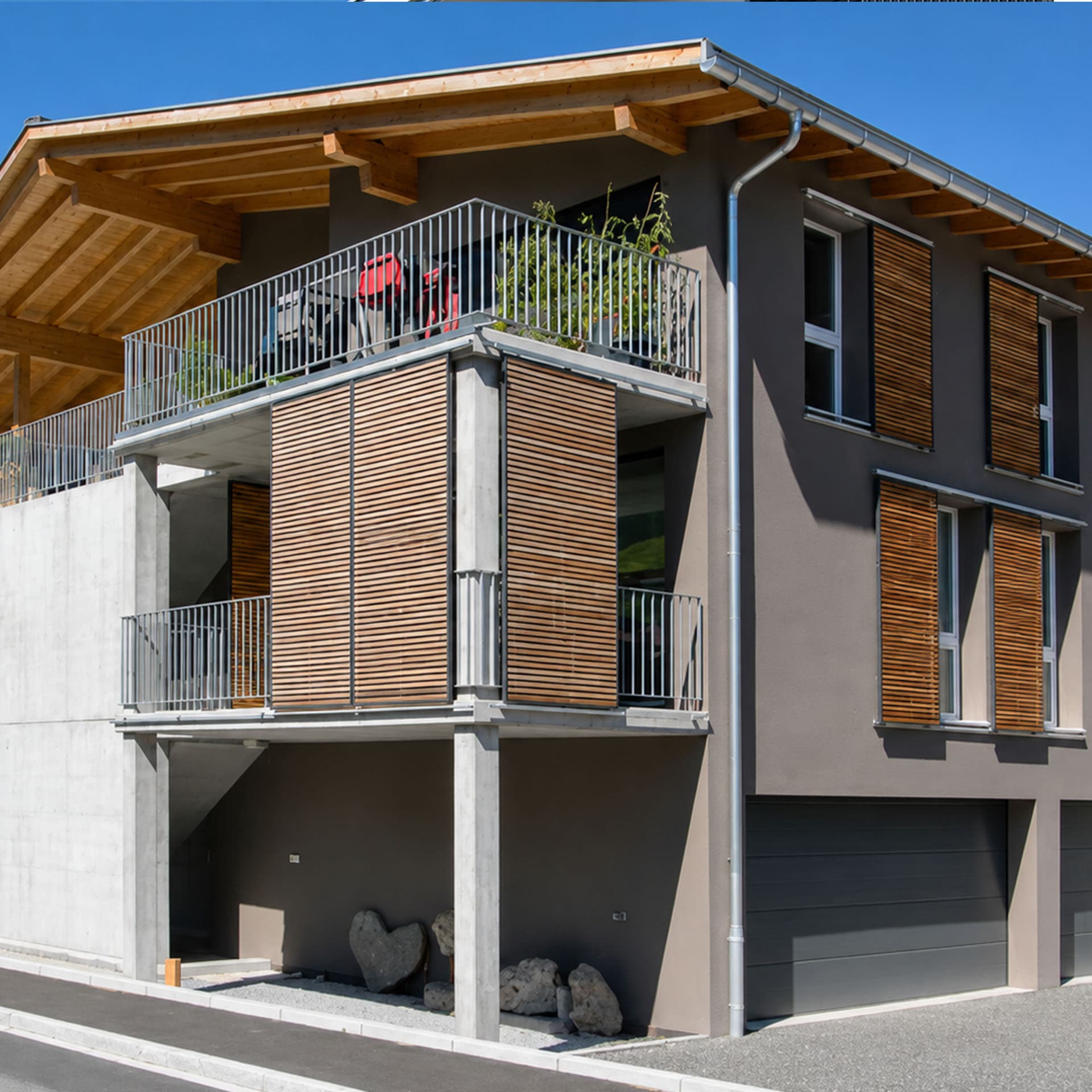 Mehrfamilienhaus mit moderner Fassade und Schiebeläden aus Lärchenholz