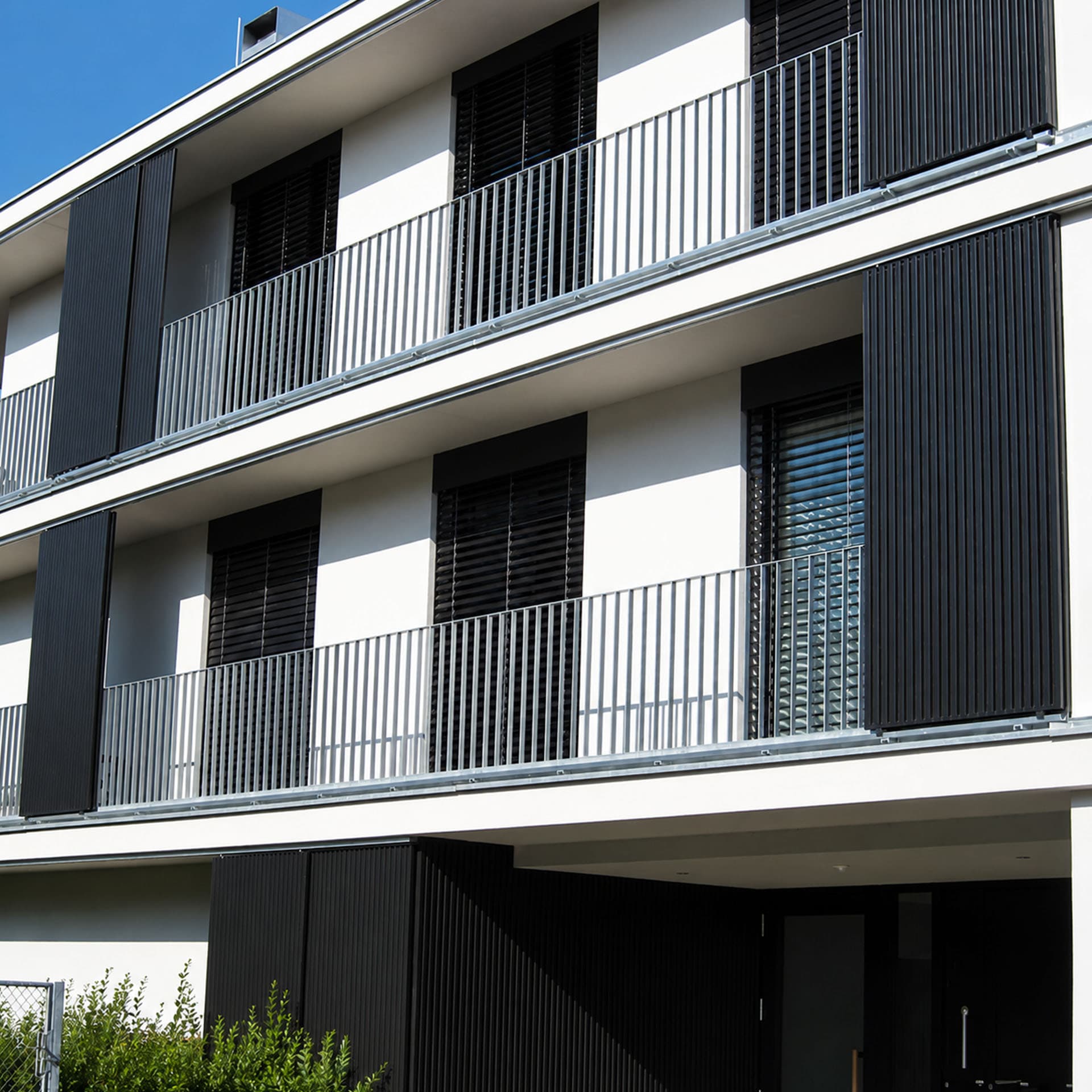 Kleine Wohnanlage mit moderner Fassade und dunklen Schiebeläden